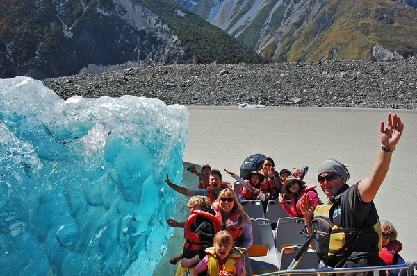 Up close and personal &#8211; passengers on a Glacier Explorers trip touch blue ice on the base of an iceberg